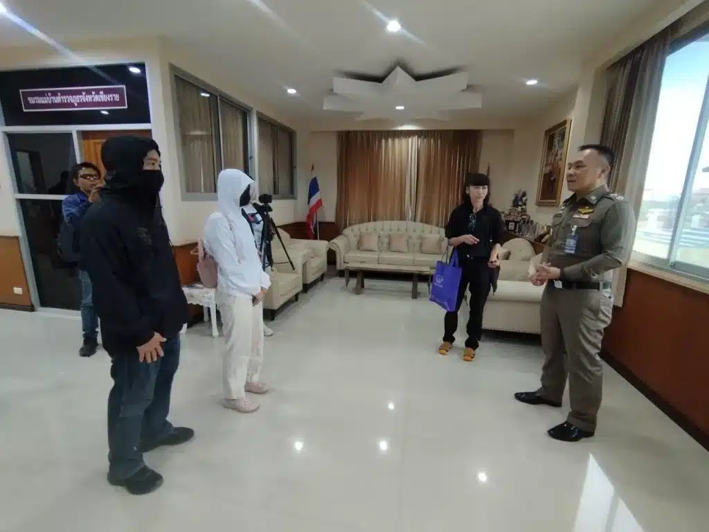 สาวเชียงรายป่วยโปลิโอ เล่านาทีหนีแก๊งสแกมเมอร์กัมพูชา เหยื่อในตึกเดิมหนีออกมาได้อีกนับสิบ
หญิงสาวชาวเชียงรายที่ป่วยโปลิโอ เดินทางพร้อมพ่อเข้าไปขอบคุณตำรวจ หลังประสานช่วยเหลือให้กลับไทยได้อย่างปลอดภัย เธอเล่าว่า ก่อนหน้านี้ถูกหลอกไปทำงานเป็นแอดมินที่สระแก้ว สุดท้ายกลับถูกพาข้ามแดนไปปอยเปต ถูกยึดบัตรประชาชนและโทรศัพท์ แล้วถูกบังคับสแกนหน้าเพื่อทำธุรกรรมโอนเงิน
พ่อลูกเข้าขอบคุณตำรวจ หลังช่วยพากลับไทย
วันที่ 24 ก.พ. นายอุดร ชาว บ้านแซว อำเภอเชียงแสน จังหวัดเชียงราย พาลูกสาว น.ส.นภัศรา อายุ 23 ปี ซึ่งป่วยโปลิโอ เข้าพบและขอบคุณ พล.ต.ต.มานพ เสนากุล ผู้บังคับการตำรวจภูธรจังหวัดเชียงราย หลังตำรวจในพื้นที่ร่วมกับตำรวจภูธรภาค 5 ช่วยประสานงานจนเธอหนีออกจากขบวนการหลอกลวงในกัมพูชา และกลับถึงไทยได้
ถูกชวนทำงานแอดมิน เงินเดือน 20,000 ก่อนพาไปชายแดน
น.ส.นภัศราเล่าว่า เธอเคยทำงานแอดมินติดต่อประสานลูกค้าในกรุงเทพฯ แต่เมื่อว่างงานจึงหางานผ่านออนไลน์ ต่อมาพบเฟซบุ๊กรับสมัครงานแอดมินที่จังหวัดสระแก้ว เสนอเงินเดือน 20,000 บาท จึงตัดสินใจสมัคร
จากนั้น ผู้ชักชวนให้นัดขึ้นรถที่ห้างสรรพสินค้า ย่านลาดพร้าว กรุงเทพฯ เมื่อวันที่ 12 ก.พ. 2569 เพื่อเดินทางไปสระแก้ว ระหว่างทางมีผู้สมัครร่วมไปด้วยประมาณ 5-6 คน
ถึงสระแก้วแล้วไม่ตรงปก ถูกพาเข้าพื้นที่ไร่อ้อยและบังคับข้ามแดน
เมื่อไปถึงจังหวัดสระแก้ว กลุ่มดังกล่าวถูกพาไปแวะห้างสรรพสินค้าในพื้นที่ ก่อนจะถูกพาขึ้นรถกระบะไปยังไร่อ้อยที่ไม่ทราบพิกัด แล้วถูกบังคับให้วิ่งผ่านไร่อ้อยไปอีกฝั่ง
น.ส.นภัศราซึ่งพิการระดับ 3 จากโปลิโอ ต้องเดินเขย่งฝ่าทางจนสุดแนวไร่ ต่อมามีชาวกัมพูชาประมาณ 4 คนมารับตัว แล้วพาขึ้นรถกระบะเข้าเขตเมืองปอยเปต ประเทศกัมพูชา
ถูกยึดบัตรและโทรศัพท์ ก่อนบังคับสแกนหน้าโอนเงิน
เธอบอกว่า เมื่อไปถึงตึกที่ใช้เป็นฐานของแก๊งสแกมเมอร์ กลุ่มคนร้ายยึดบัตรประชาชนและโทรศัพท์ ทำให้ครอบครัวติดต่อไม่ได้ จากนั้นยังบังคับให้สแกนใบหน้าผ่านแอปธนาคารในมือถืออย่างน้อย 3 ครั้ง เพื่อทำรายการโอนเงินเข้าและออก
ในตึกเดียวกัน เธอสังเกตว่ามีคนไทยอยู่จำนวนมาก ราว 30-40 คน หลายคนพยายามหาทางหนี บางส่วนรวมตัวกันก่อเหตุเผาตึกเพื่อเปิดทางหลบออกมา
"ตอนนั้นกลัวมาก อยากกลับบ้านอย่างเดียว" เธอเล่า
ถูกย้ายไปกาสิโนเมืองไพลิน ได้โทรศัพท์คืนจึงขอความช่วยเหลือ
ต่อมาวันที่ 16 ก.พ. กลุ่มคนร้ายส่งเธอไปอยู่ที่ Grand Pailin Casino & Resort ในเมืองไพลิน ใกล้ปอยเปต ครั้งนี้เธอได้โทรศัพท์และเอกสารคืน ทำให้สามารถใช้ Wi-Fi ติดต่อพ่อ และขอความช่วยเหลือไปยังตำรวจที่เกี่ยวข้อง
ขณะเดียวกัน คนไทยที่ยังอยู่ตึกเดิมในปอยเปตทราบว่าเกิดเหตุวุ่นวายและมีไฟไหม้ หลายคนจึงวิ่งหนีออกมา และมีบางส่วนข้ามกลับฝั่งไทยได้
รวมตัวหนีอีก 5 คน วิ่งข้ามแดนกลับไทยทางสระแก้ว
น.ส.นภัศราบอกว่า เมื่อเห็นโอกาสจึงชวนคนไทยอีก 5 คน หนีออกมาด้วยกัน ได้แก่
* น.ส.กมลเนตร อายุ 45 ปี ชาวนครราชสีมา
* น.ส.รุ่ง อายุ 35 ปี ชาวอุทัยธานี
* น.ส.บุญยารัตน์ อายุ 29 ปี ชาวนครปฐม
* นายกิตติศักดิ์ อายุ 27 ปี ชาวขอนแก่น
* นายอาทิมา อายุ 25 ปี ชาวหนองคาย
ทั้งหมดนั่งรถรับจ้างไปลงบริเวณป่าไผ่ใกล้ชายแดน ก่อนวิ่งฝ่ากลับเข้าประเทศไทย และมีทหารไทยตามแนวชายแดนช่วยเหลือจนเข้าพื้นที่จังหวัดสระแก้วได้
หลังจากนั้น เจ้าหน้าที่ส่งทุกคนเข้าสู่กระบวนการคัดกรอง และมีการเปรียบเทียบปรับตามขั้นตอน เนื่องจากเข้าออกชายแดนผิดกฎหมาย ก่อนแยกย้ายกลับภูมิลำเนา
ด้านน.ส.นภัศราเข้าแจ้งความที่ สภ.เชียงแสน ระบุว่าถูกหลอกไปทำงานต่างประเทศจนเข้าข่ายเป็นเหยื่อค้ามนุษย์
ตำรวจเตือน งานง่ายเงินดีผิดปกติ ให้ระวังการชวนไปทำงานชายแดน
พล.ต.ต.มานพกล่าวว่า ดีใจที่ครอบครัวได้ลูกสาวกลับมาอย่างปลอดภัย พร้อมย้ำเตือนประชาชนให้ระวังการชักชวนผ่านเฟซบุ๊ก โดยเฉพาะงานแอดมินที่บอกว่าไม่ต้องมีทักษะ งานสบาย แต่ให้เงินเดือนสูง 20,000-40,000 บาท เพราะถือว่าน่าสงสัย
ยิ่งถ้ามีการนัดให้เดินทางไปพื้นที่ชายแดนไทยกัมพูชา ให้คิดว่าเป็นพื้นที่เสี่ยง และอาจถูกพาออกนอกประเทศได้
"ไม่มีงานไหนให้ข้อเสนอง่าย แต่ได้เงินแพงแบบนี้" เขากล่าว
ส่วนคดีนี้ ตำรวจจะสอบปากคำและตรวจสอบหลักฐาน เพื่อดำเนินการตามขั้นตอนต่อไป