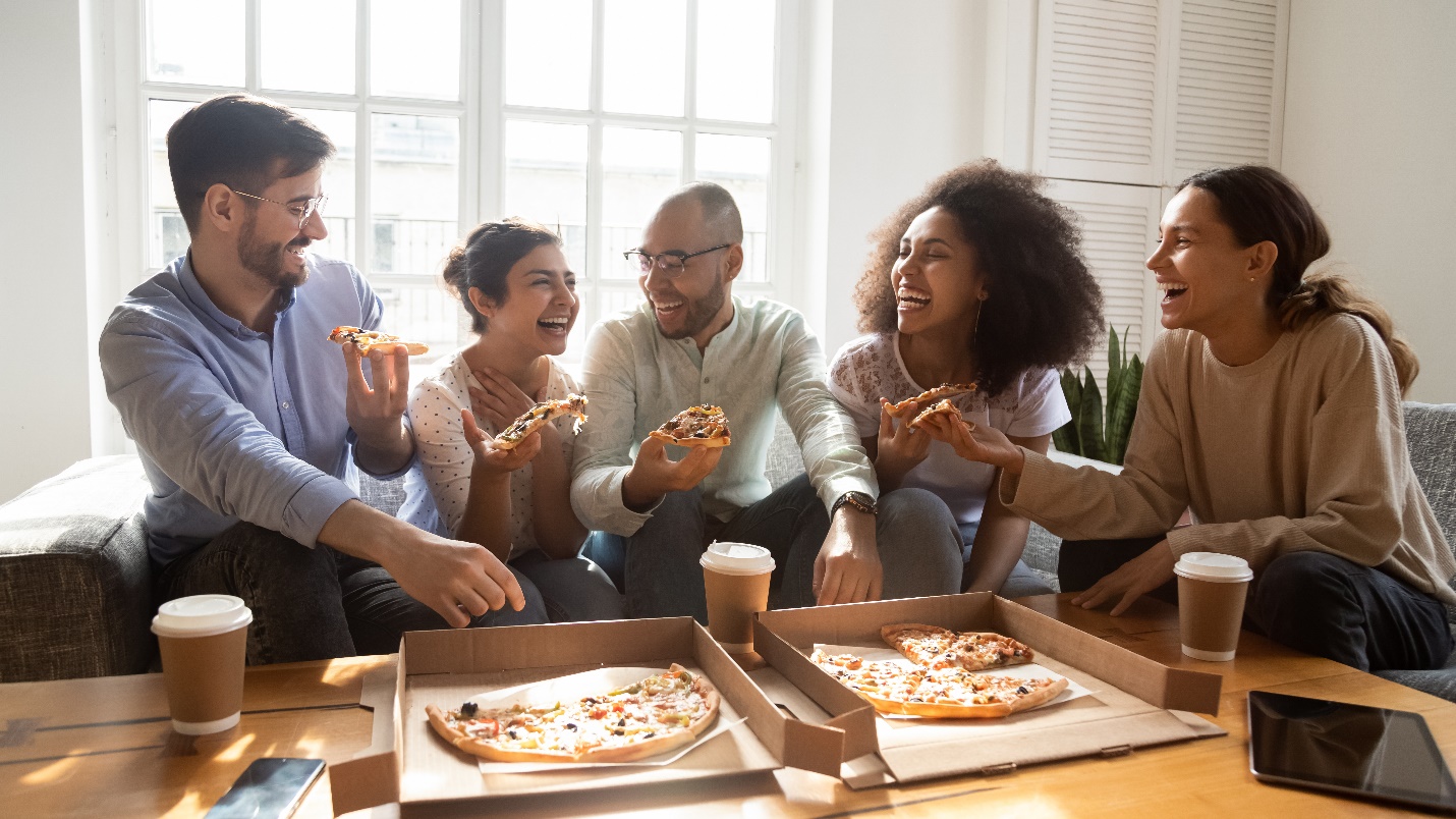 A group of people sitting around a table with pizzas

Description automatically generated with medium confidence