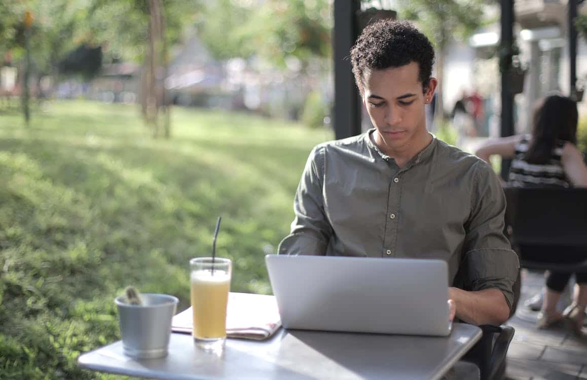 Free Focused black male freelancer using laptop in street cafe Stock Photo