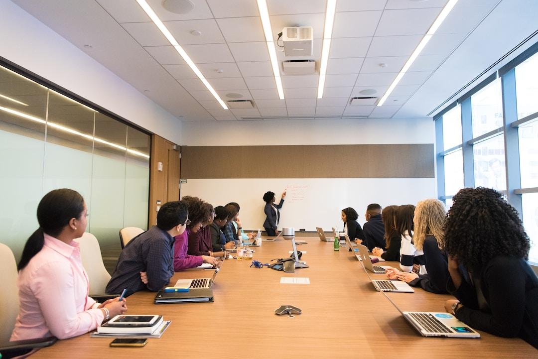 A meeting in a conference room, a team sits at a table with laptops, and a leader explains RFP management.