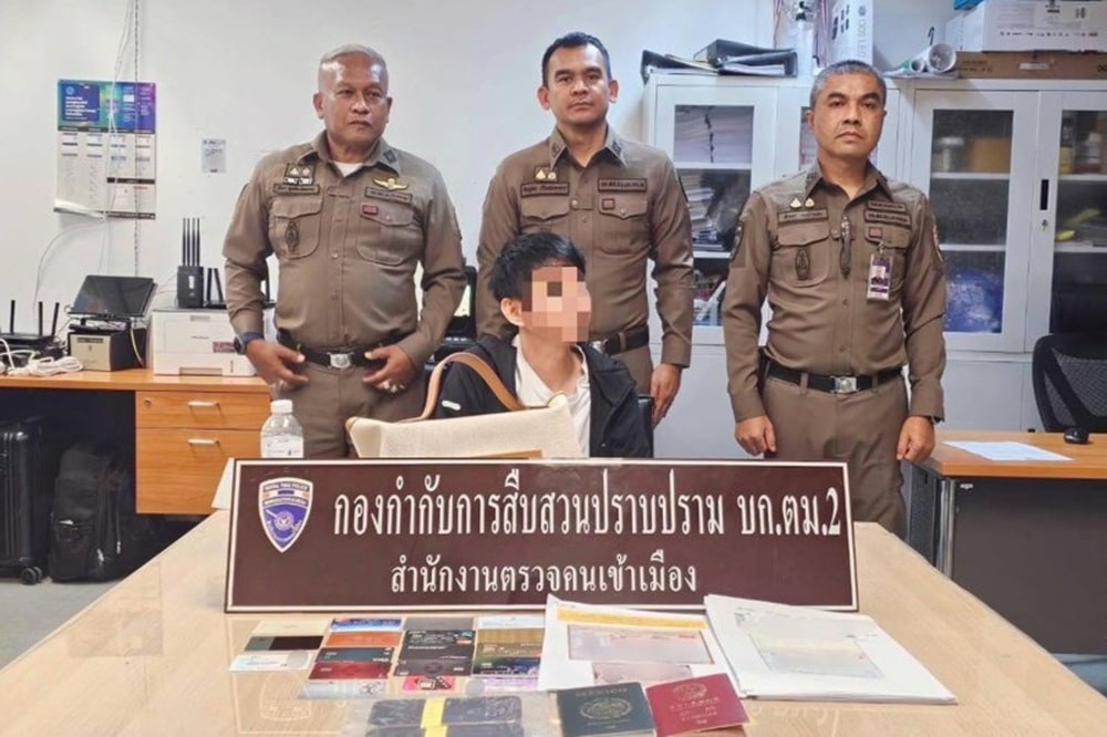 A Chinese fugitive wanted on an Interpol Red Notice is seen along with some of the evidence seized by immigration police officers at Suvarnabhumi airport